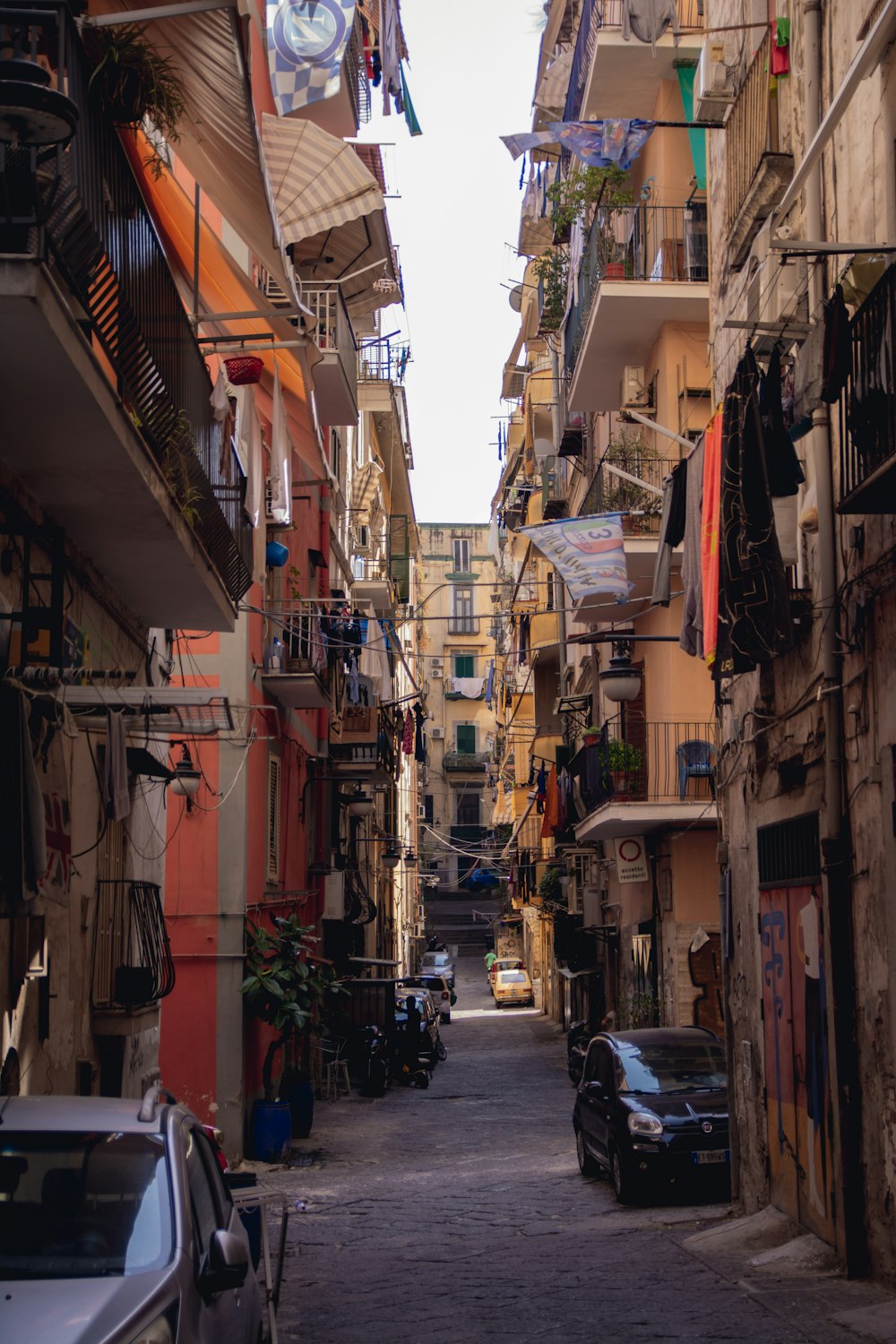 a narrow city street with cars parked on both sides