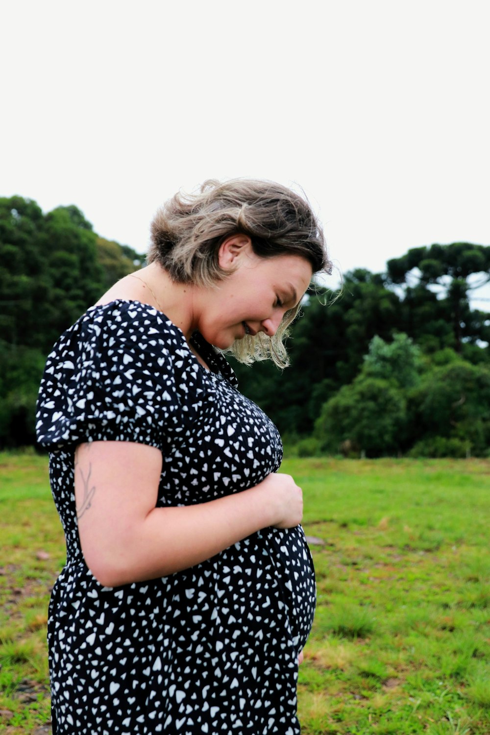 uma mulher grávida em um vestido preto e branco em pé em um campo