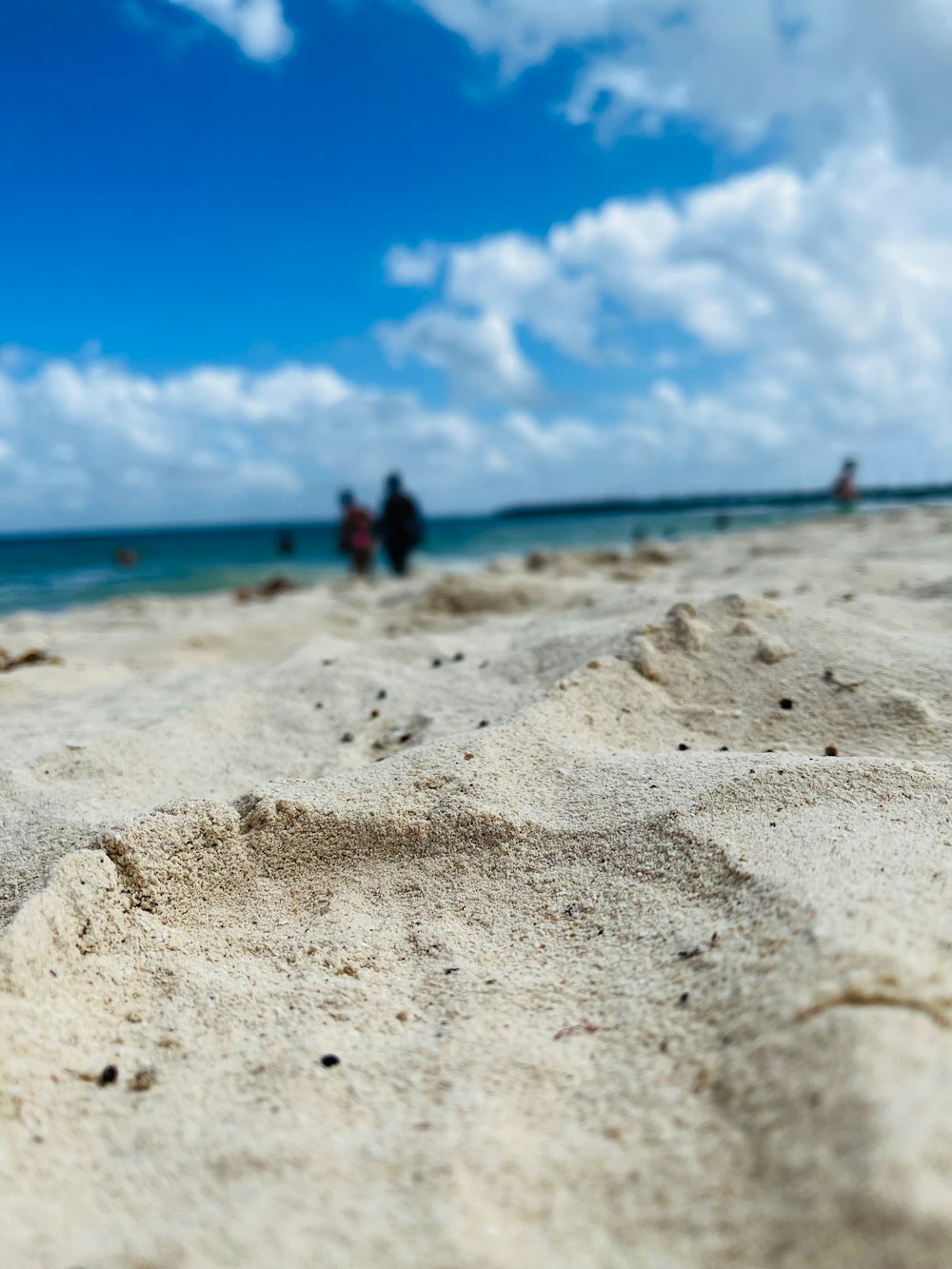 a close up of sand on a beach with people in the background