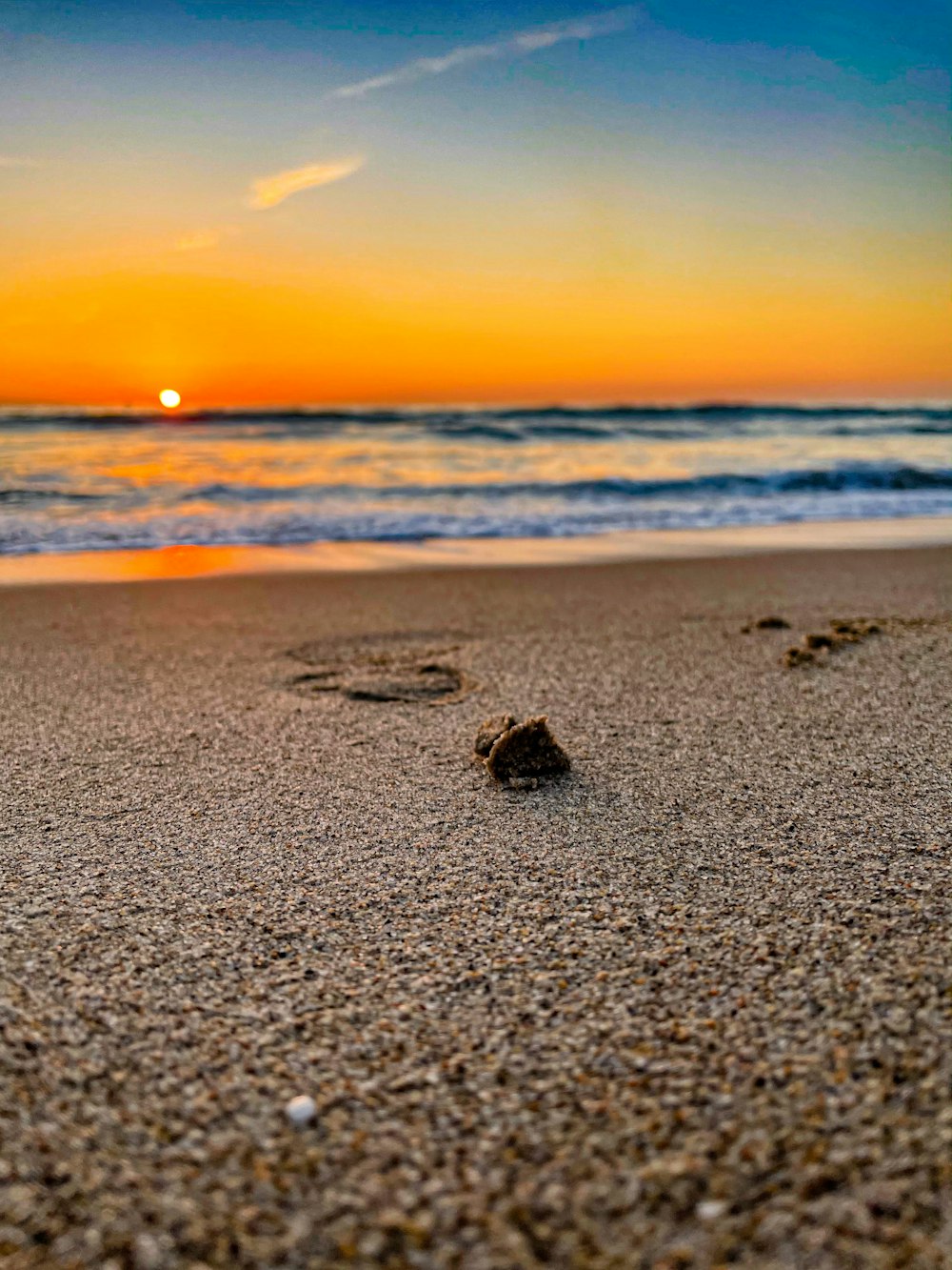 footprints in the sand of a beach at sunset