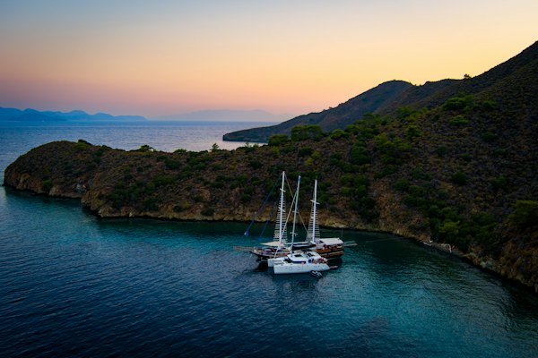 A gulet anchored under a wooded headland on the Datça peninsula at dusk