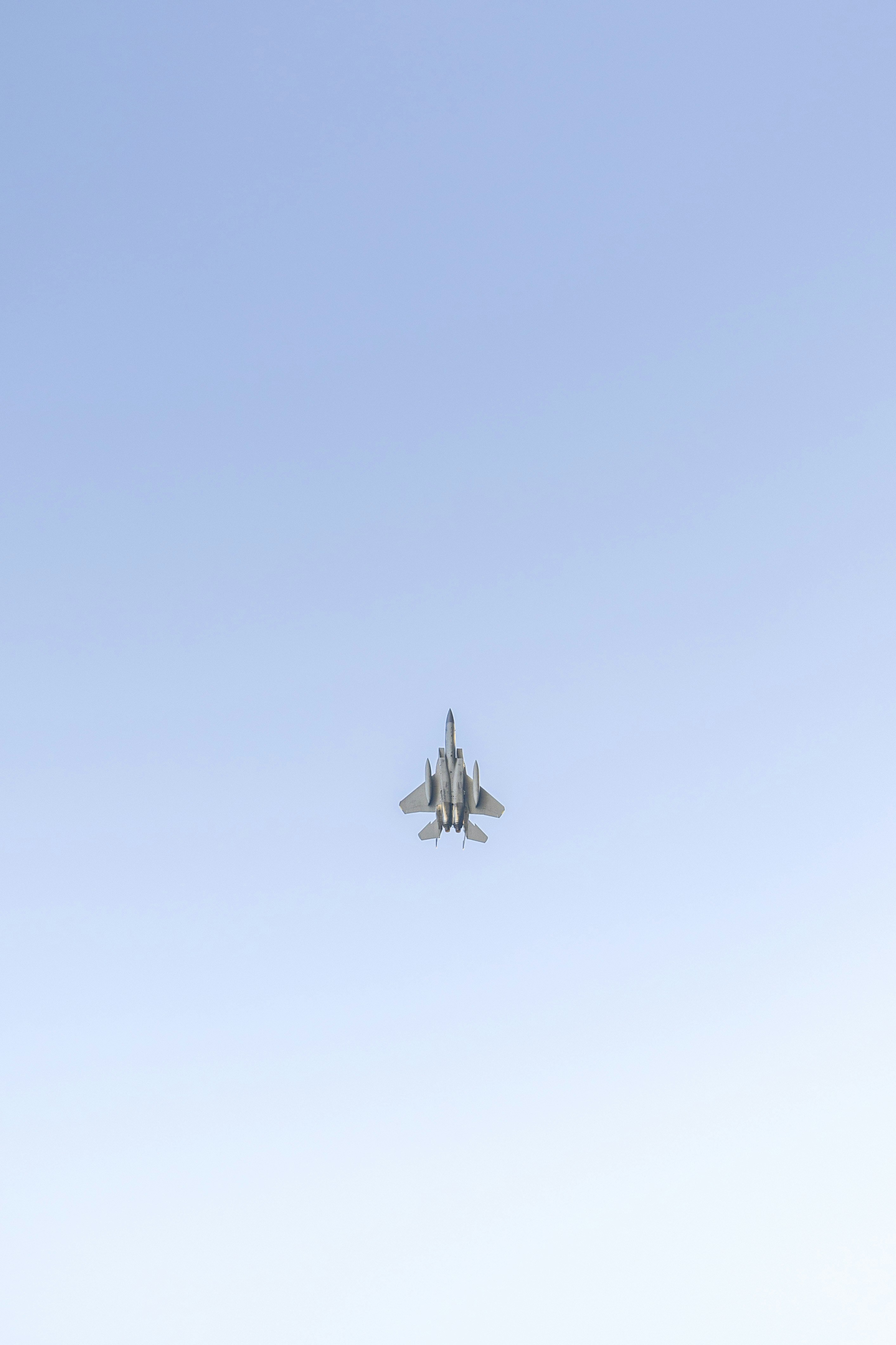 a fighter jet flying through a blue sky