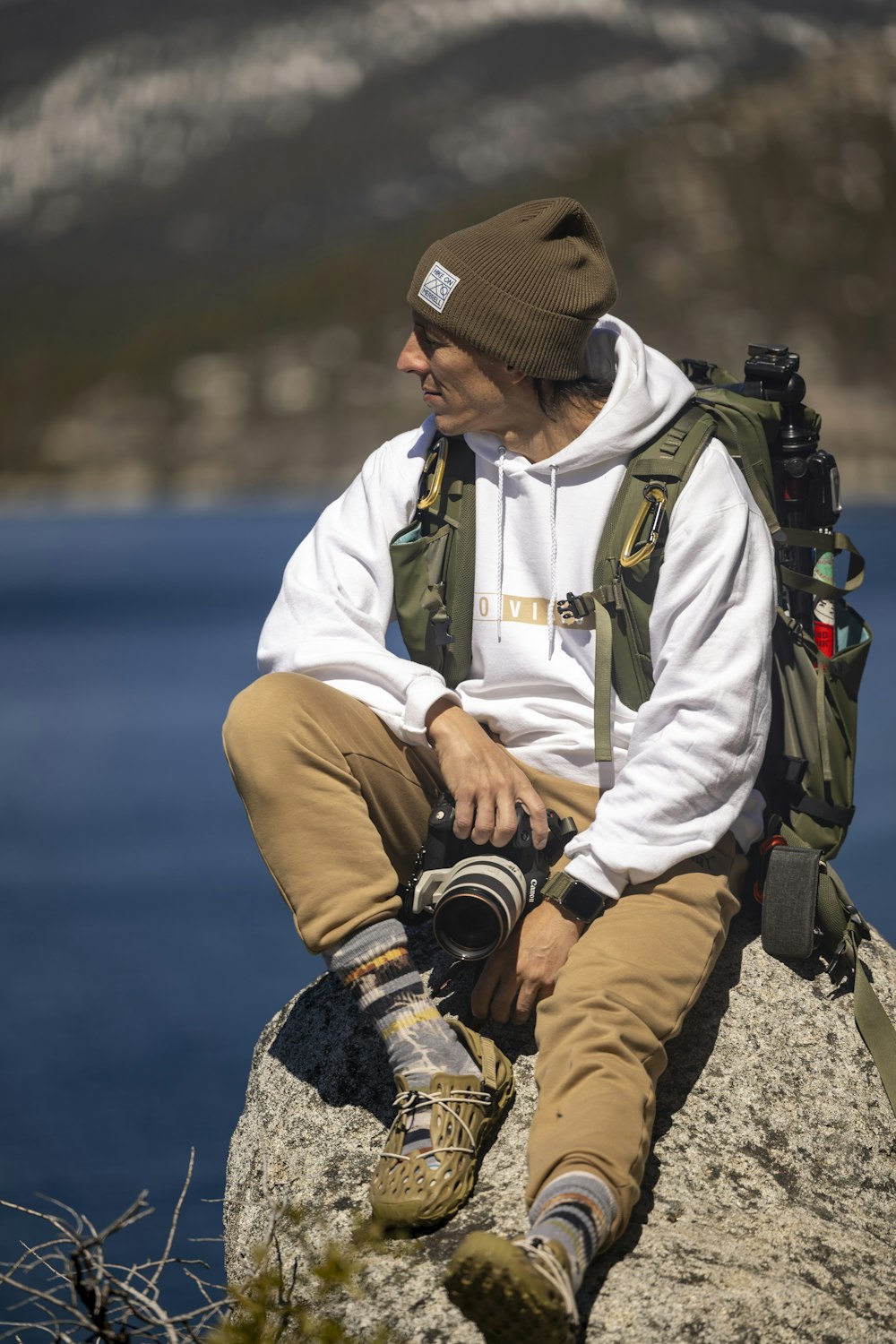 a man sitting on top of a rock next to a body of water