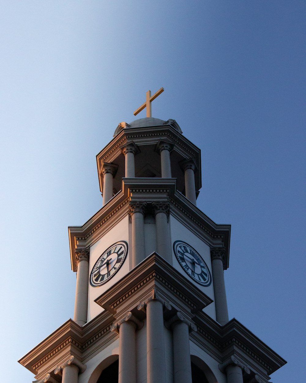 a clock tower with a cross on top of it