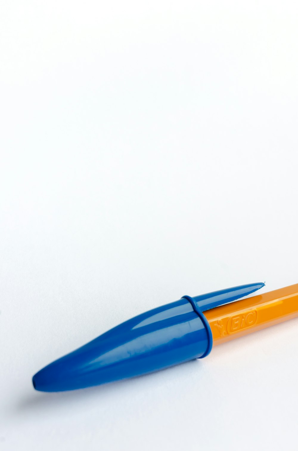 Ein blau-orangefarbener Stift sitzt auf einem weißen Tisch
