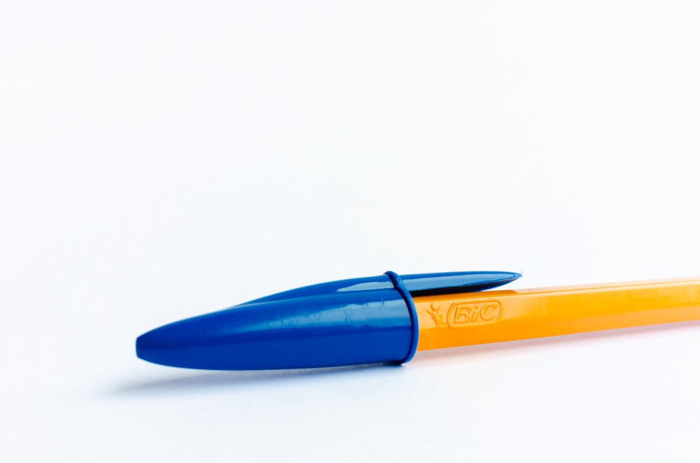 a blue and yellow pen sitting on top of a white surface