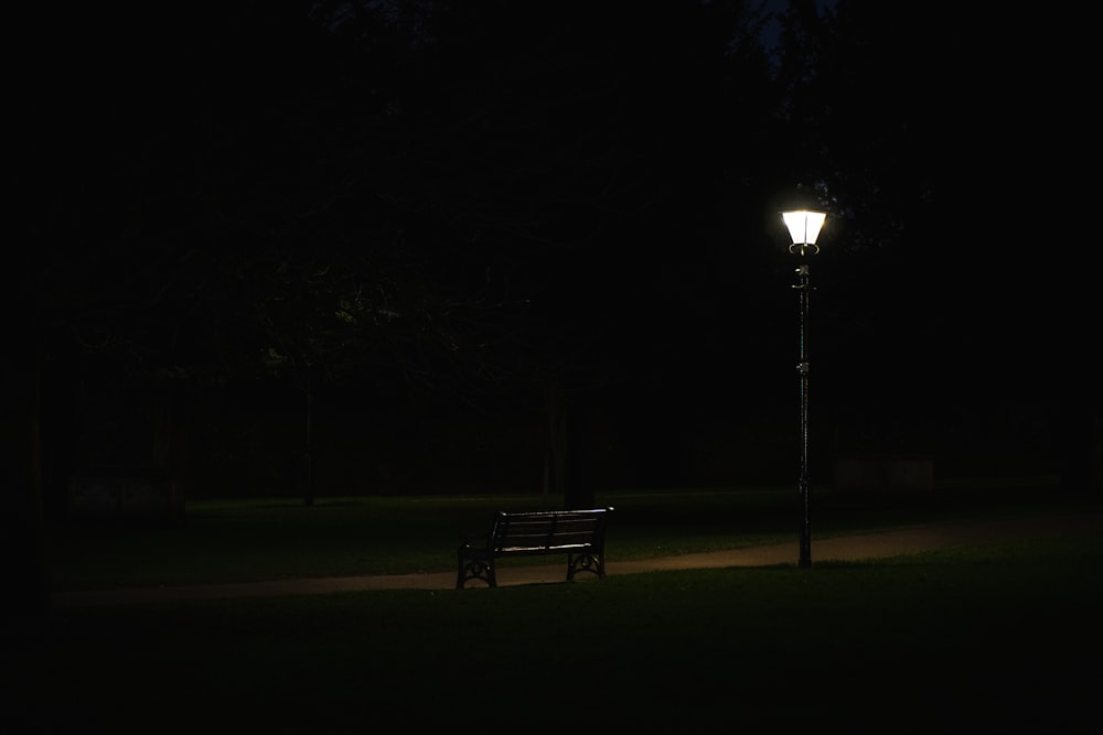 a park bench sitting under a street light at night