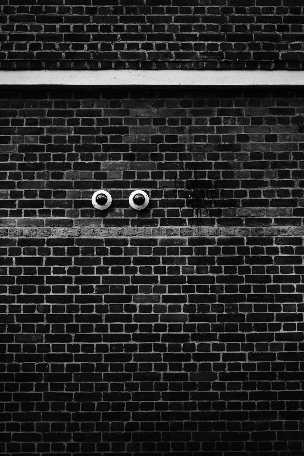  a black and white photo of two eyes on a brick wall