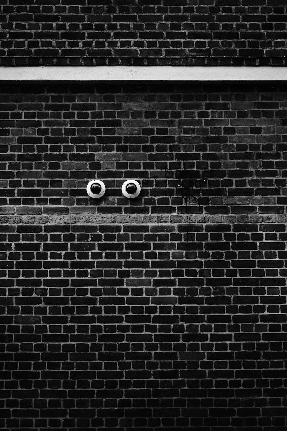 a black and white photo of two eyes on a brick wall