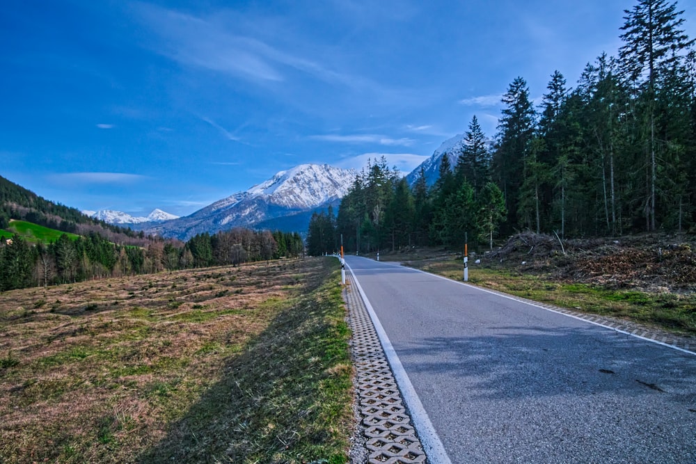 eine Straße mitten auf einem Feld mit Bergen im Hintergrund