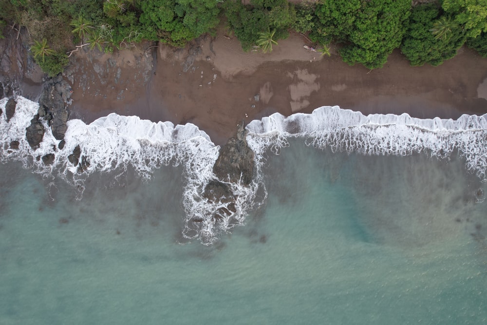 an aerial view of a beach with waves crashing on the shore