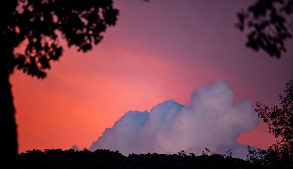 a large cloud is in the sky at sunset