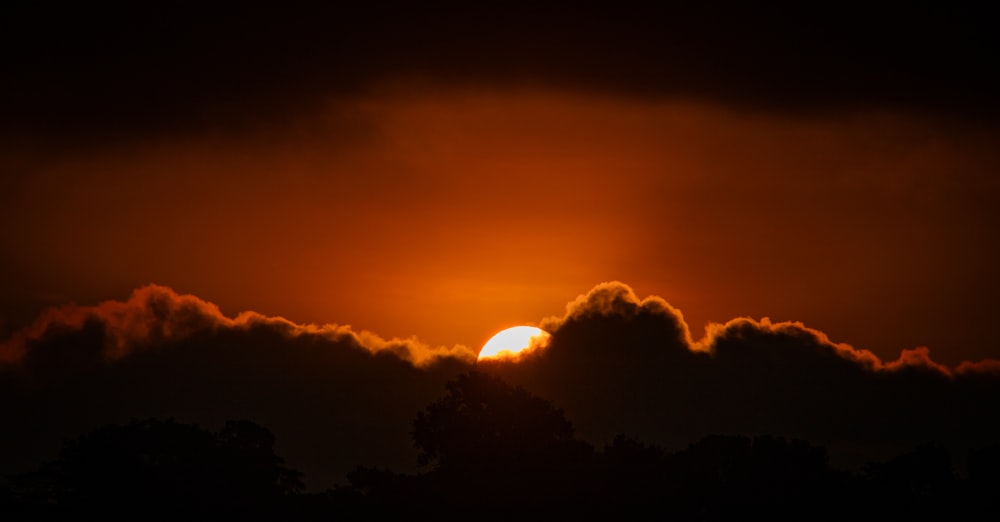 the sun is setting behind some clouds in the sky