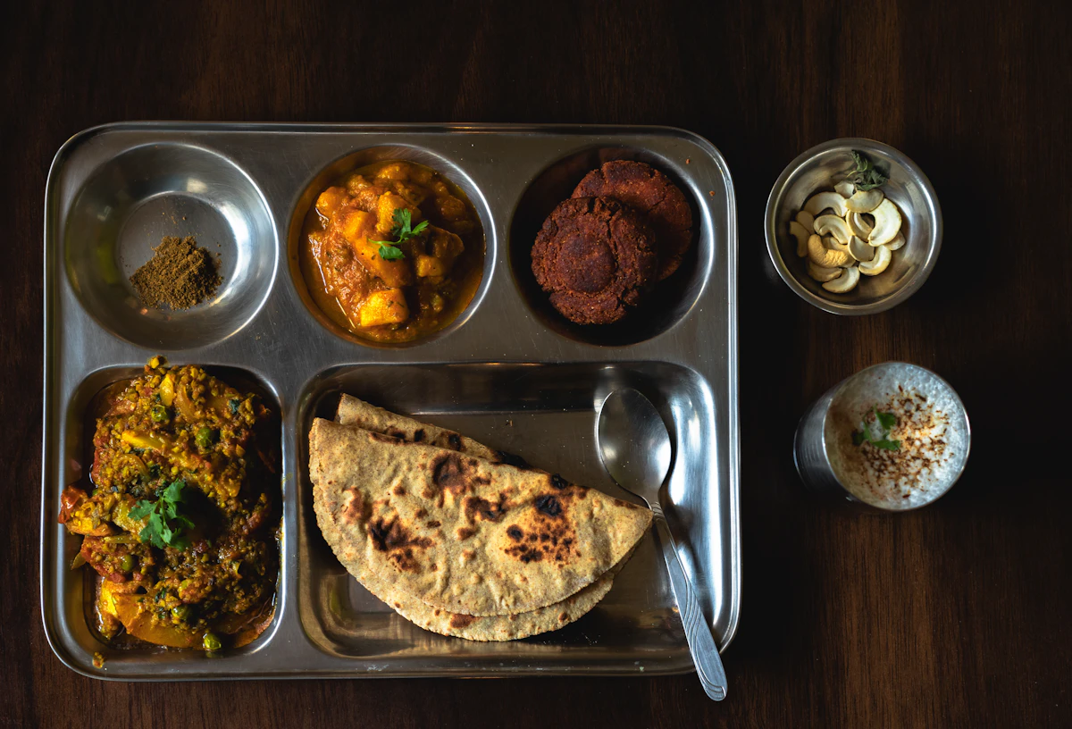 A thali with many small bowls of curries and sides