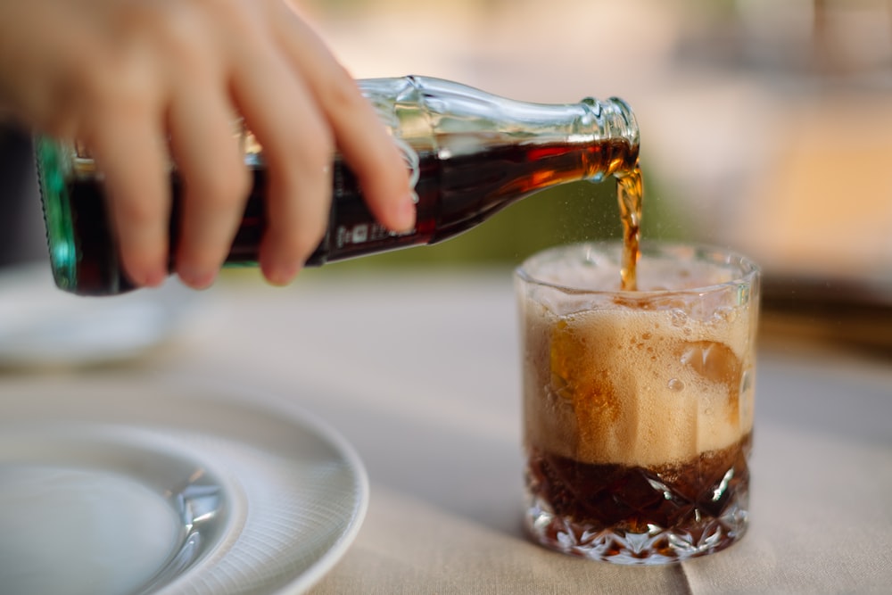 a person pouring a beverage into a glass