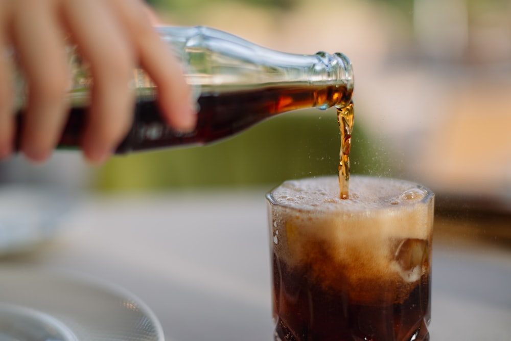 a person pouring a beverage into a glass