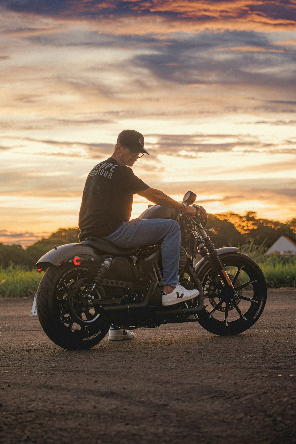 um homem sentado em uma motocicleta em uma estrada de terra