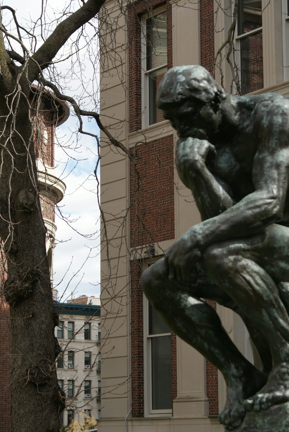 a statue of a man sitting in front of a tree