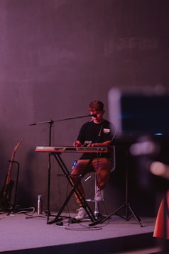 a man sitting at a keyboard in front of a microphone