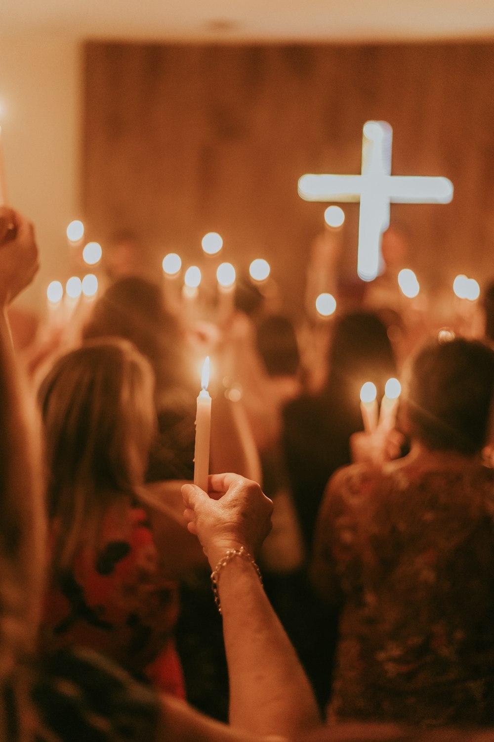 a group of people holding candles in front of a cross