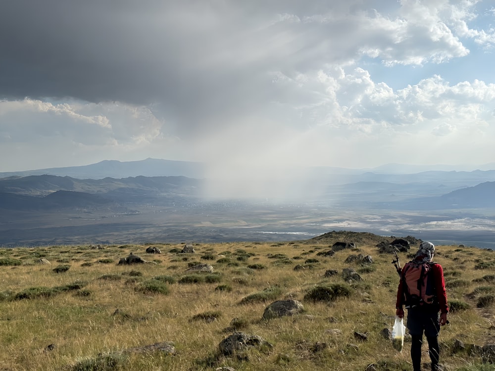 a man standing on top of a grass covered hillside