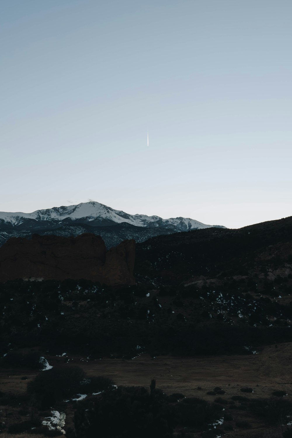 a view of a mountain with a plane flying in the sky