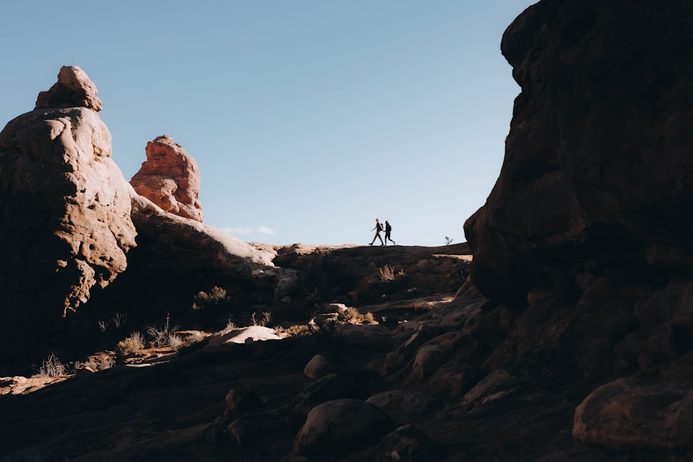 a couple of people standing on top of a rocky hillside