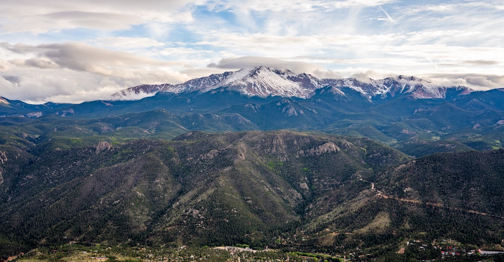 a scenic view of a mountain range with snow capped mountains in the distance