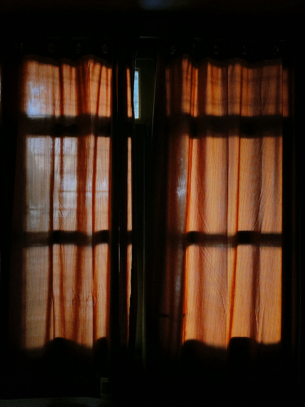 a dark room with a window covered in curtains