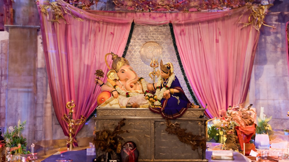 Una estatua del Señor Ganesh frente a una cortina rosa
