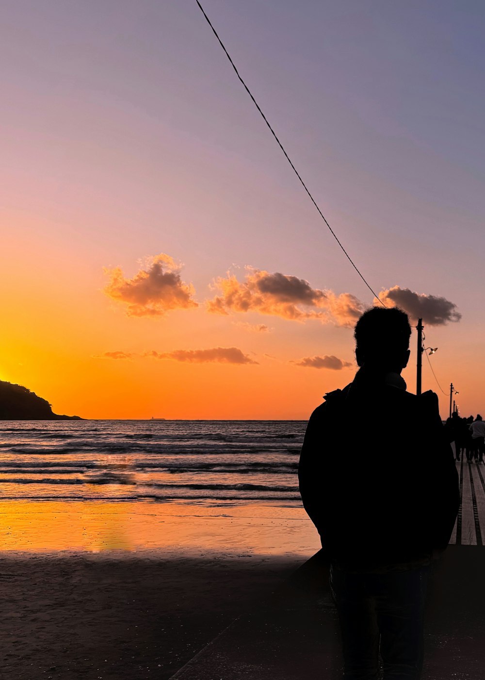 Un hombre parado en la playa viendo la puesta de sol