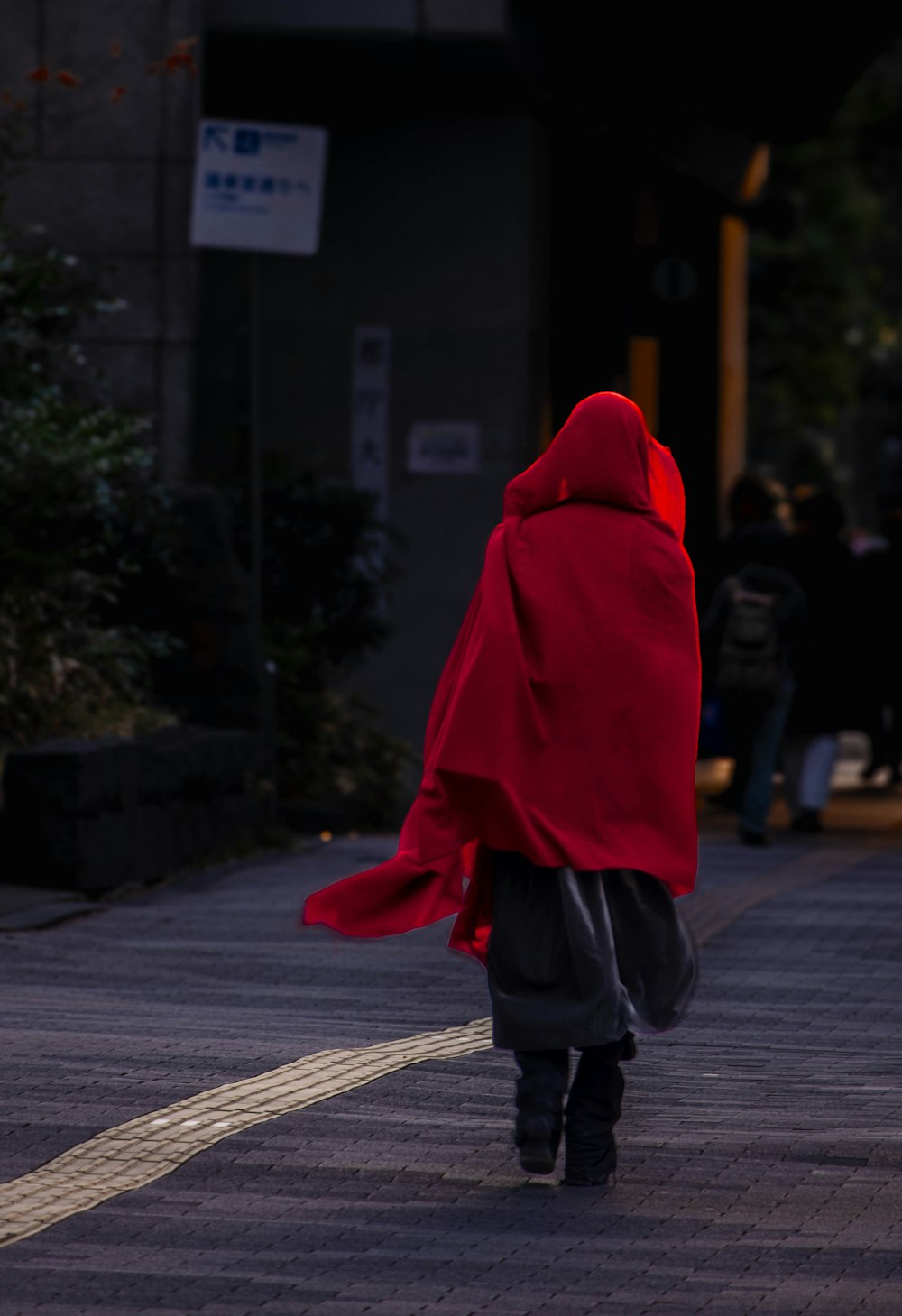 a person in a red cloak walking down a street