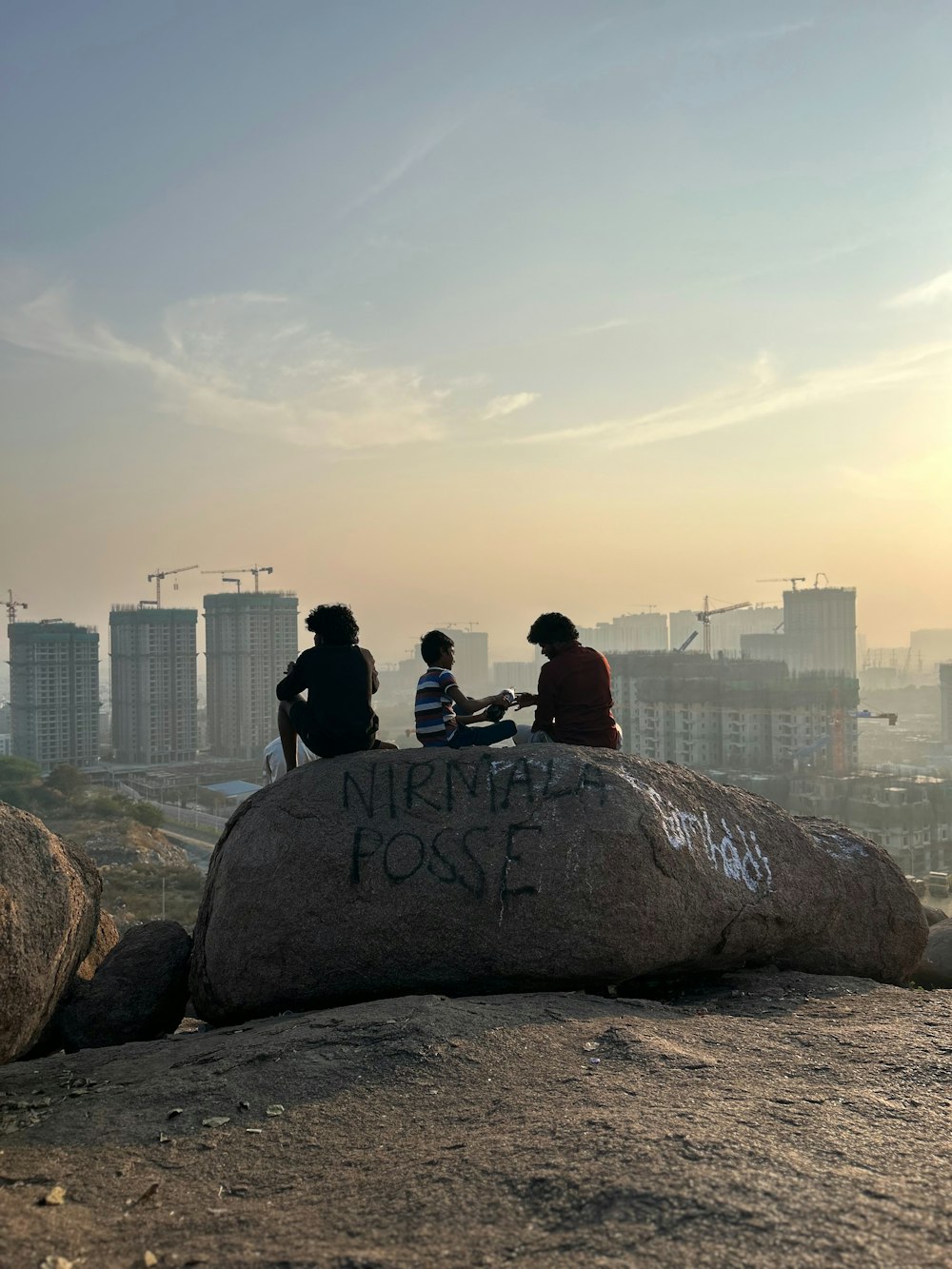 three people sitting on top of a large rock