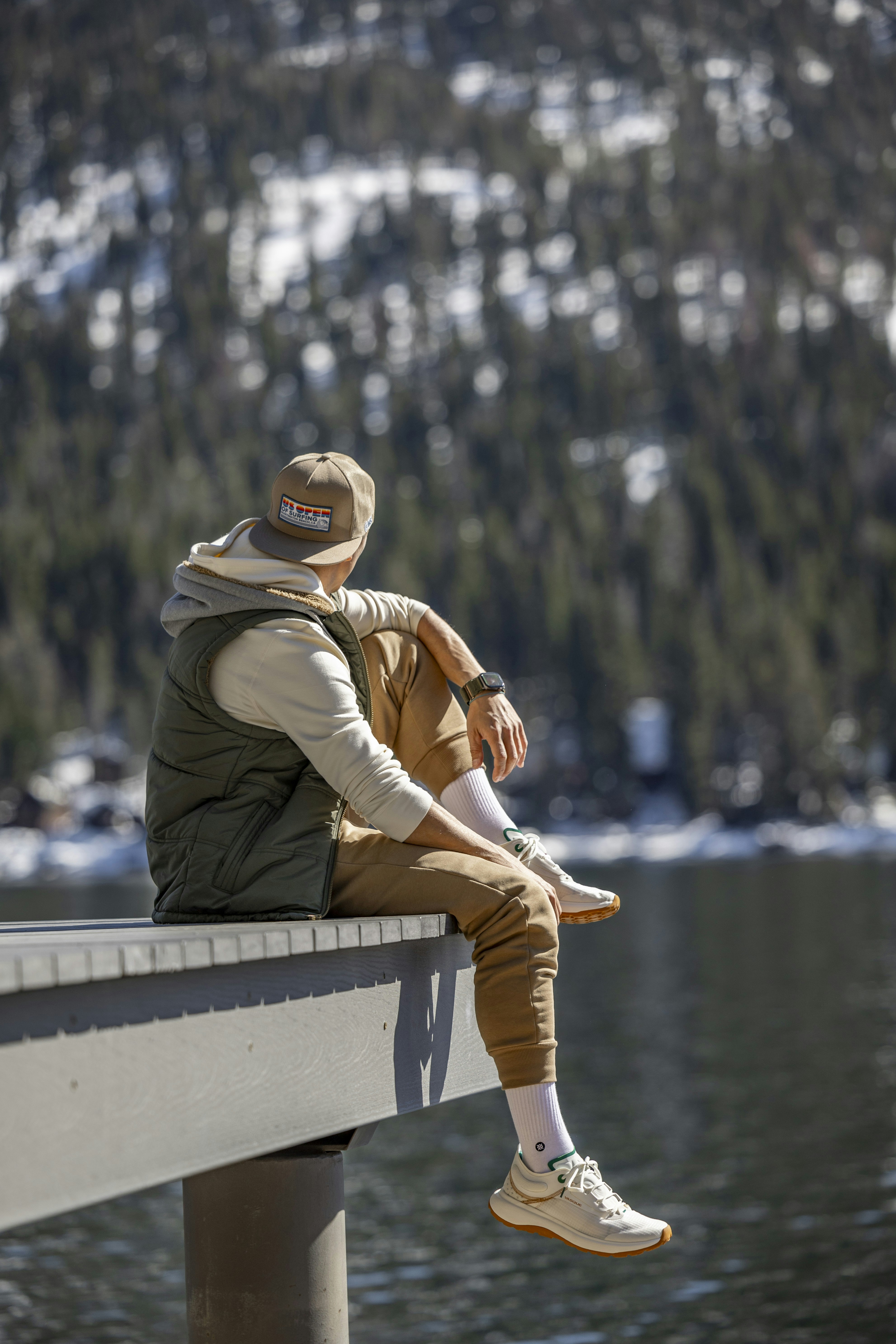 a man sitting on a bench next to a body of water