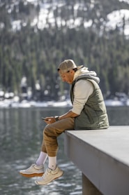 a man sitting on a ledge looking at his cell phone