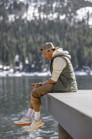 a man sitting on a ledge looking at his cell phone