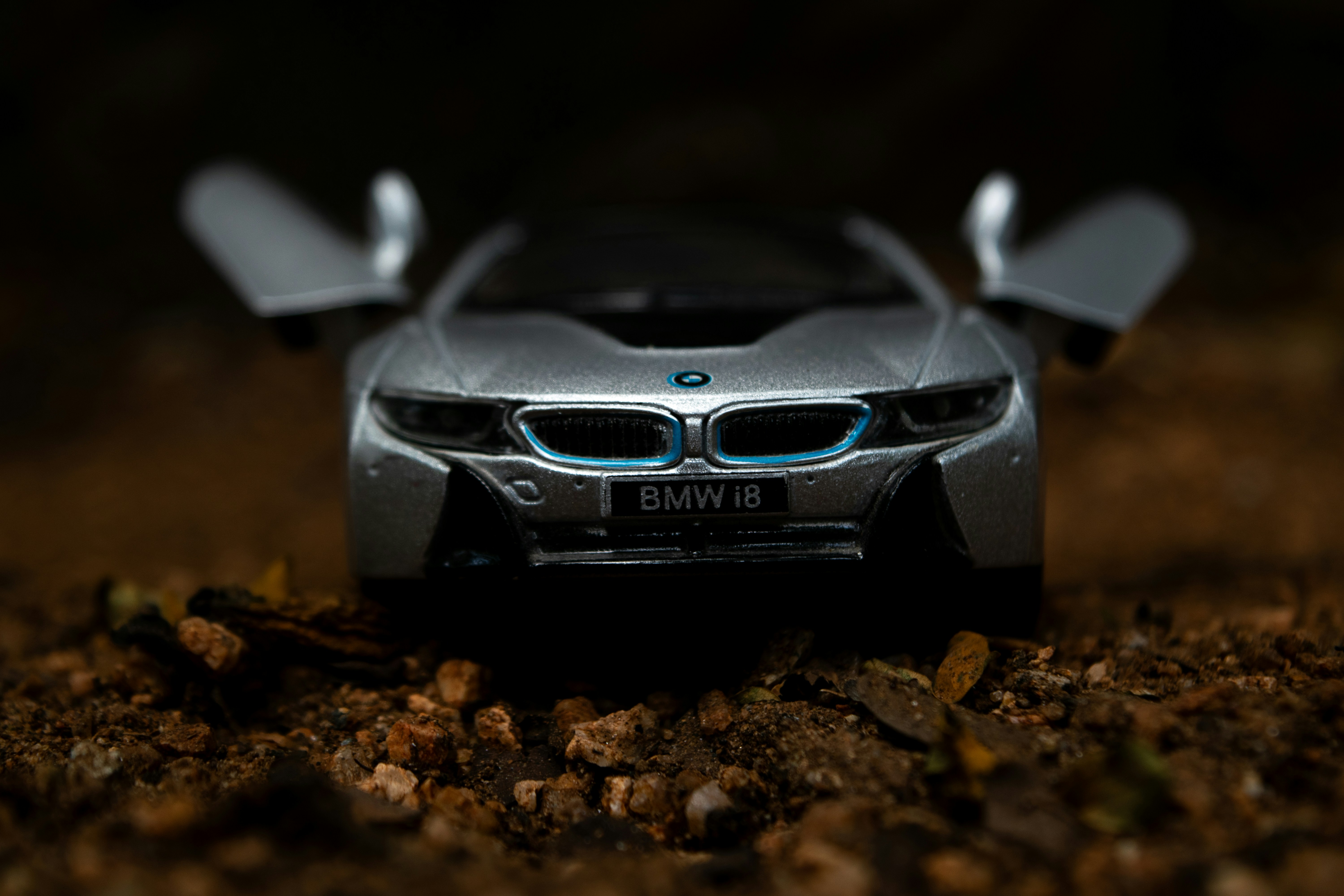 a silver toy car sitting on top of a pile of dirt