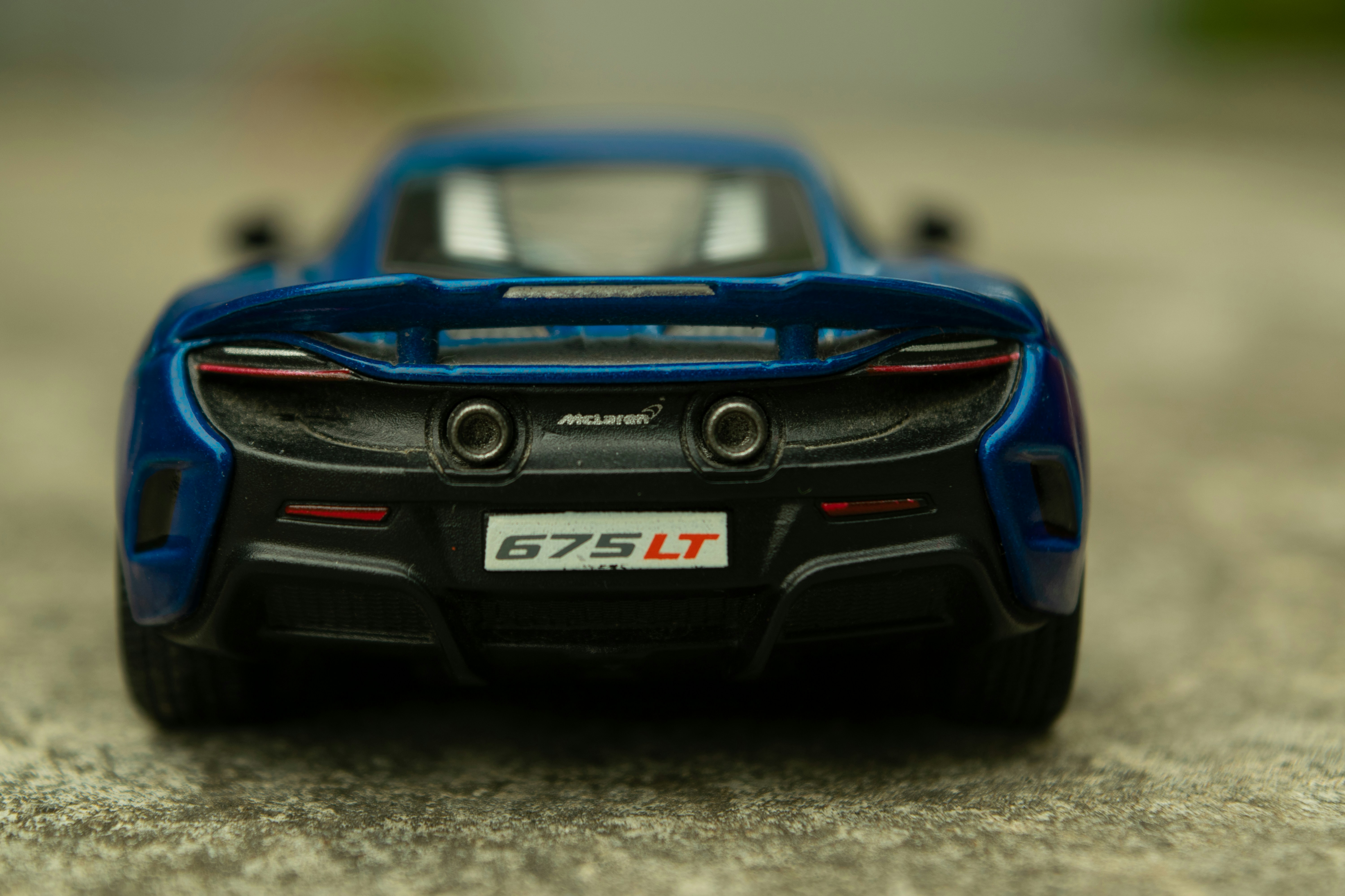 a blue toy car sitting on top of a cement floor