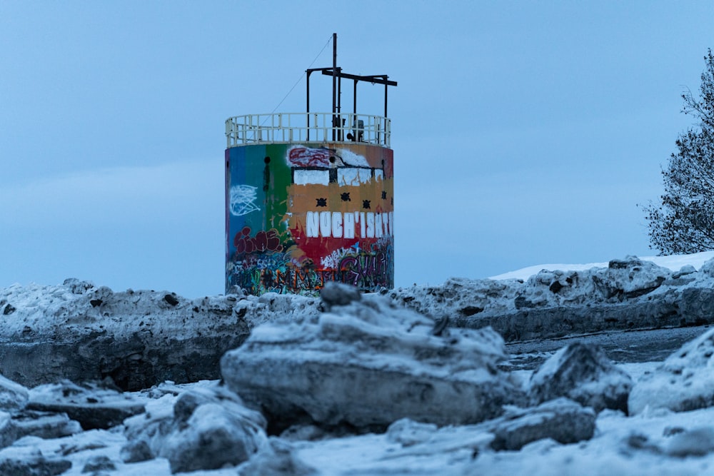 a water tower covered in snow next to a forest