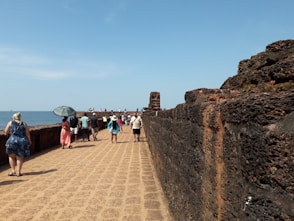 a group of people walking across a bridge next to the ocean