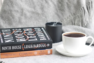 a stack of books sitting next to a cup of coffee