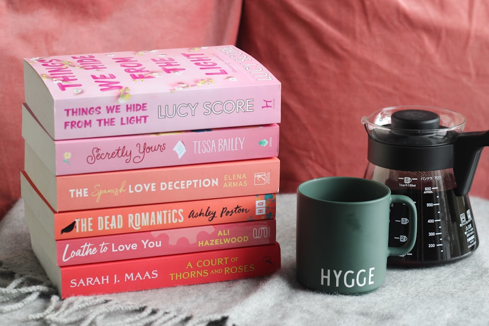 a stack of books sitting next to a coffee pot