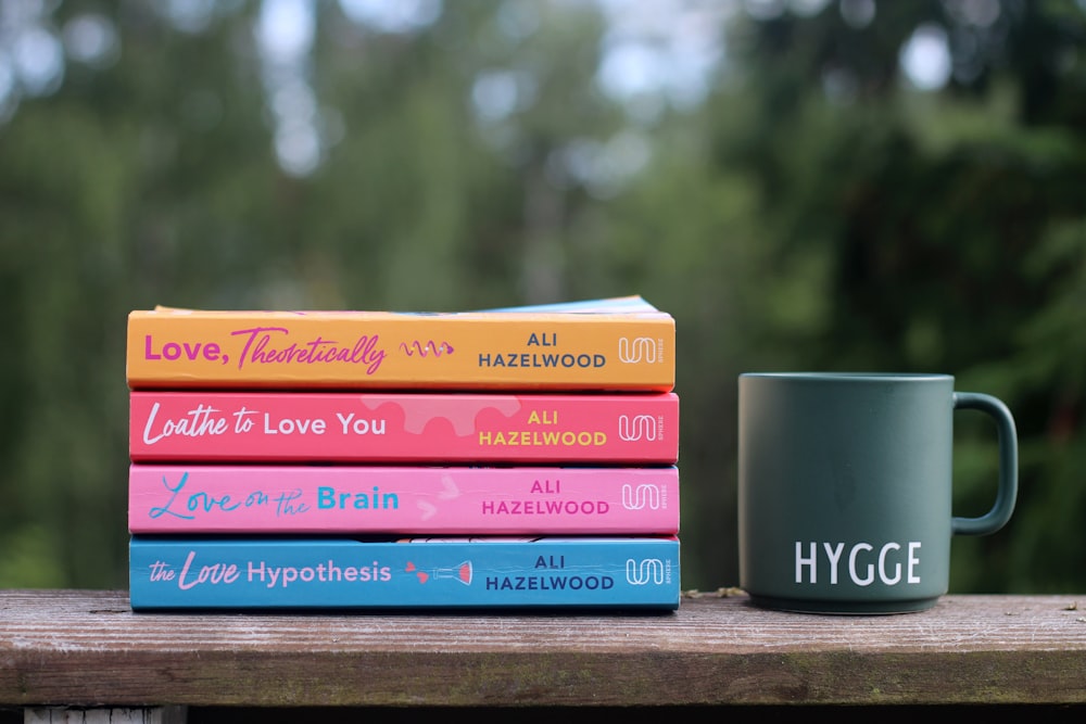 a stack of books sitting next to a coffee mug