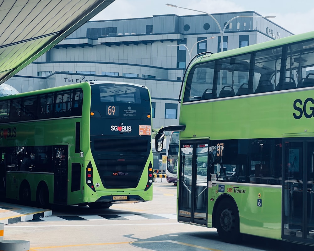 a couple of green double decker buses parked next to each other