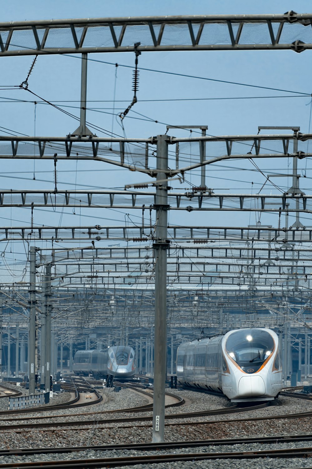 a silver train traveling down train tracks under a blue sky