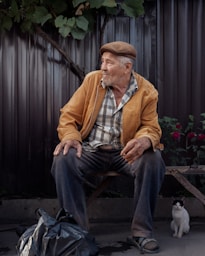 a man sitting on a bench next to a cat
