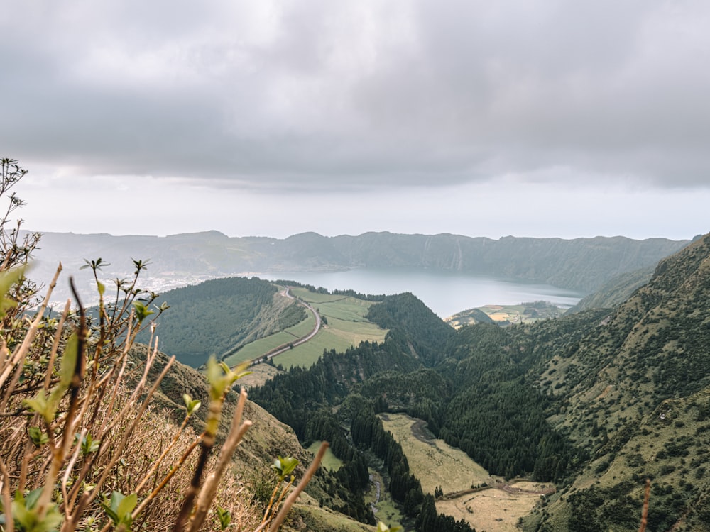 a scenic view of a valley with a lake in the distance