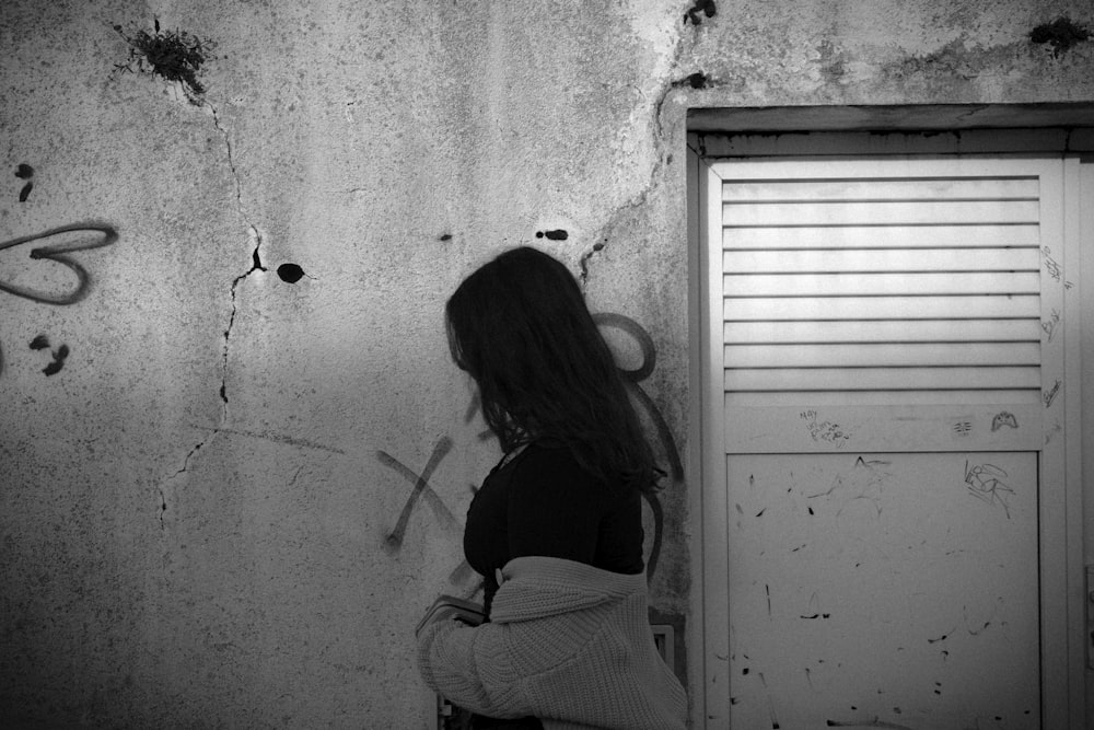 a woman standing in front of a wall with graffiti on it