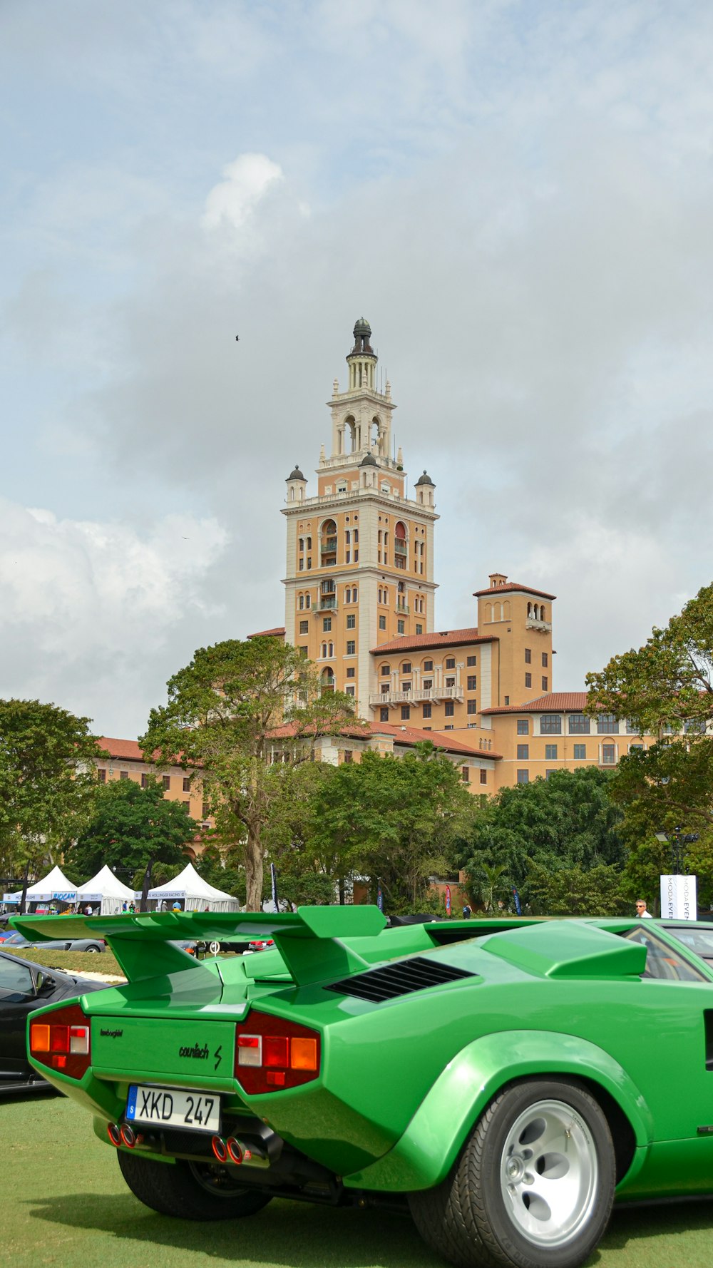 a green sports car parked in front of a tall building