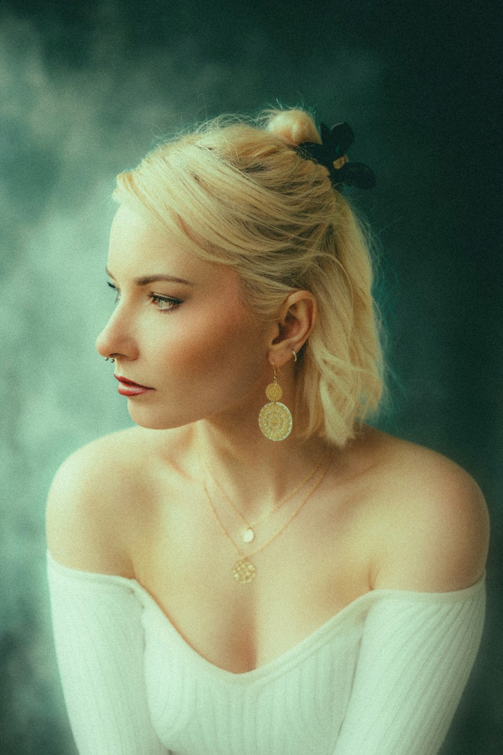 a woman wearing a white sweater and a pair of earrings